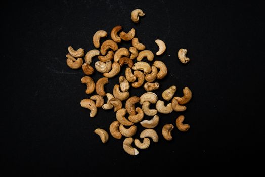 lots of cashews scattered on black background with place for text