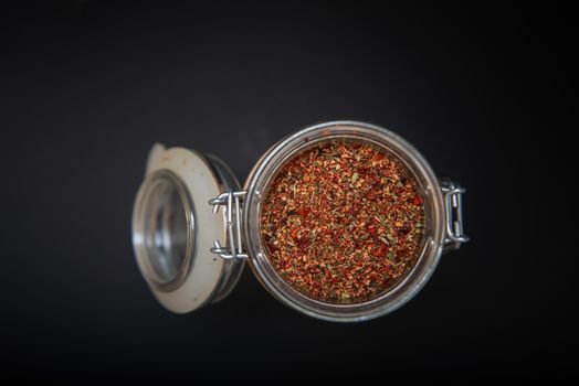 Top view of Indian spices in an open jar on a black table with copy space