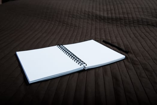 open spiral notebook to point with a pen on a textile