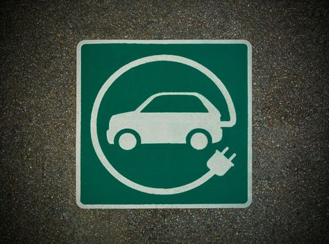 EV - electric vehicle charging station sign on asphalt. 'E' sign on asphalt texture. Image with dark corners frame