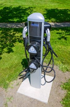 EV charger on green grass lawn. EV - electric vehicle charging station. Electric car charging point.