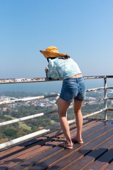 Asian pretty cute woman with hat relax and use smartphone at seaside city landscape viewpoint on mountain with happy and freedom emotion in concept travel, vacation, leisure in life