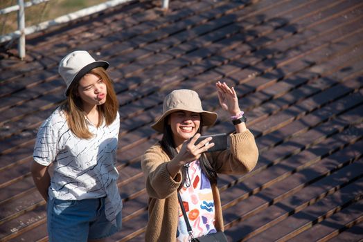 Asian pretty cute women with hat relax and use smartphone at seaside city landscape viewpoint on mountain with happy and freedom emotion in concept travel, vacation, leisure in life