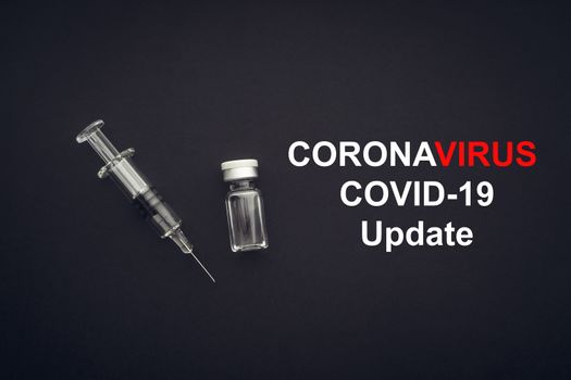CORONAVIRUS COVID-19 UPDATE text with syringe and vials on black background. Covid-19 and Coronavirus concept