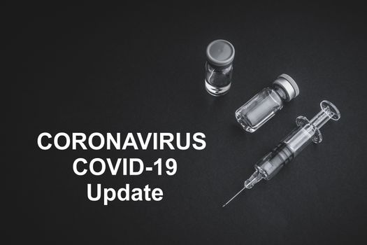 CORONAVIRUS COVID-19 UPDATE text with syringe and vials on black background. Covid-19 and Coronavirus concept