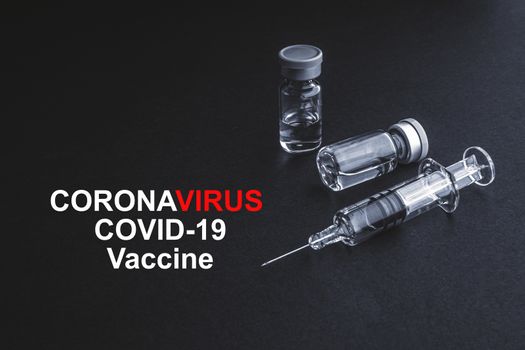 CORONAVIRUS COVID-19 VACCINE text with syringe and vials on black background. Covid-19 and Coronavirus concept