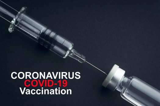 CORONAVIRUS COVID-19 VACCINATION text with syringe and vials on black background. Covid-19 and Coronavirus concept