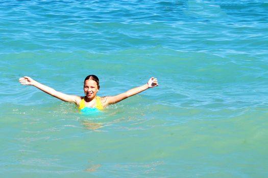 girl with hands up smiling at sea, copy space