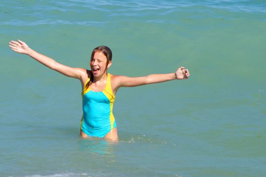 girl with hands up smiling at sea, copy space