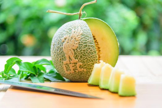 Fresh green melon with liverpool logo on wood plate