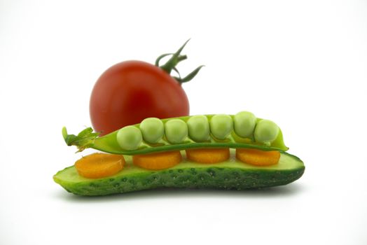 Healthy fresh vegetable sandwich over white with carrots, peas in a pod and cucumber balance on top of each other next to a red ripe tomato