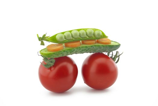 Healthy fresh vegetable still life over white with ripe red tomatoes, carrots, peas in a pod and cucumber balance on top of each other