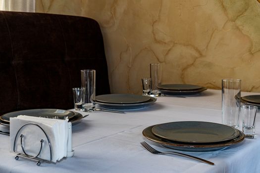 Table setting. Glass, stack, bowls and fork on the table. Cutlery on a white tablecloth