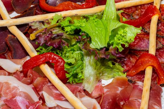 Trio of dried delicacies. Basturma, prosciutto, sausage flat. Plate with delicacies. Close up