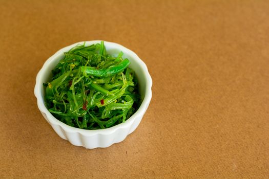 Japanese food concept. Fresh seaweed salad with sesame seeds in white bowl on black background.