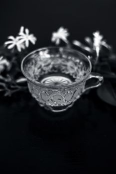 Close up of tea of Indian jasmine flower or juhi or Jasminum Auriculatum on wooden surface in a glass cup with raw flowers.