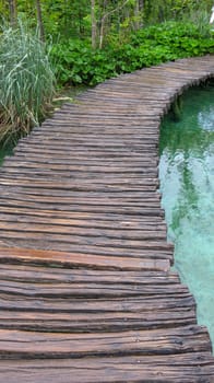 Amazing touristic wooden pathway in the colorful deep forest with clean lakes and spectacular waterfalls, Plitvice National Park, Croatia, Europe.