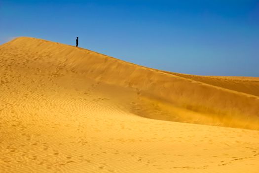 man standng on the sand of the desert with blue sky
