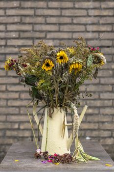 Looking slightly down at a vase of dying flower arrangement, large once bright now dying sun flowers in a vase on a very large marble dining table