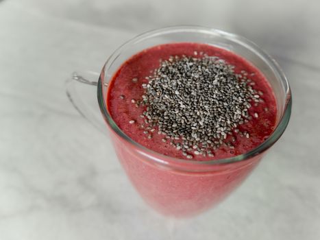 Healthy red berry smoothie with chia seeds in glass.