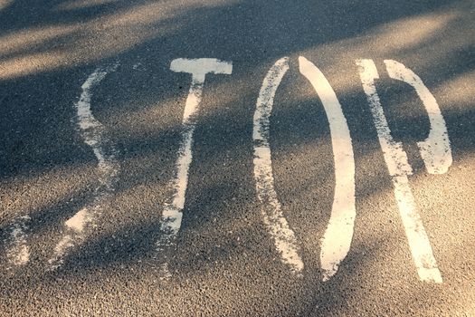 Stop word on asphalt. Warning mark written on highway ground. Traffic safety letters paint on road surface. Grunge text on transport floor.  conceptual photography of urban attention information.
