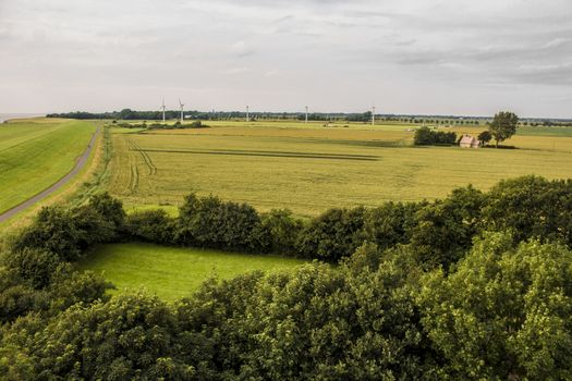 Cloudy weather, wind turbines and green grass, dike landscape in the north of Germany.