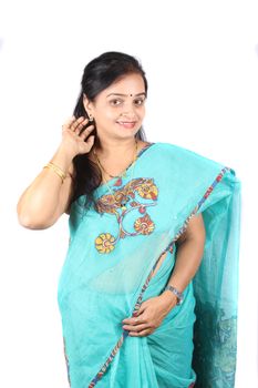 A beautiful middle aged Indian woman in saree showing her earring, on white studio background.