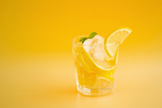 Detox Water with lemon in a glass on an orange background.