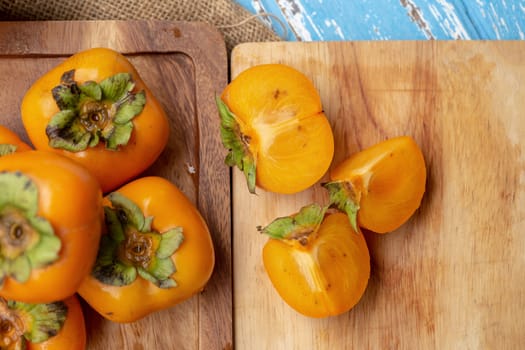 Fresh ripe persimmons on blue wooden table.