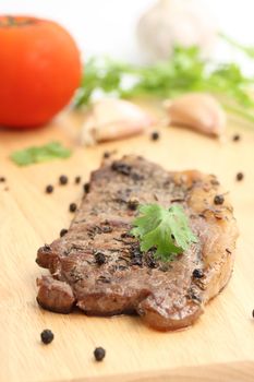 Grilled steak with vegetables on wood background