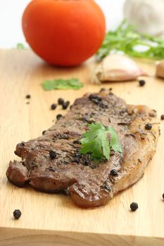 Grilled steak with vegetables on wood background