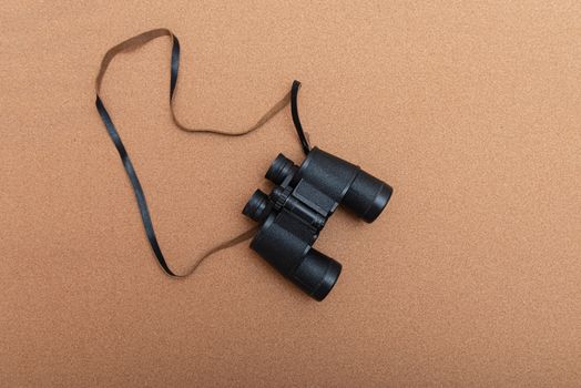 Binoculars on brown background with empty place for text