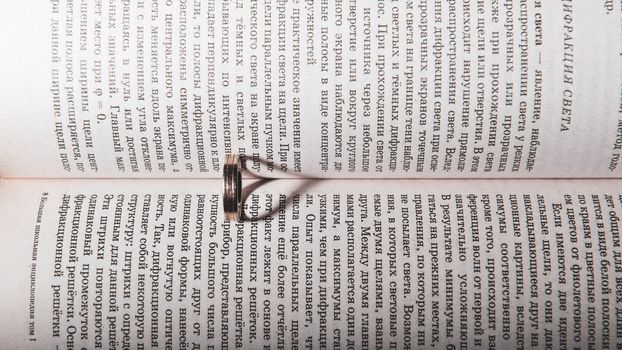 Wedding ring between the pages of an book with the sunlight casting a heart shaped shadow.