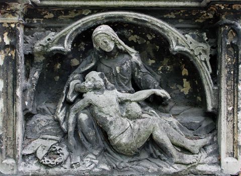 Weathered holy statue in the cemetery.