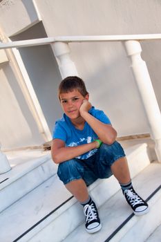 The carefree boy dreams sitting on a porch