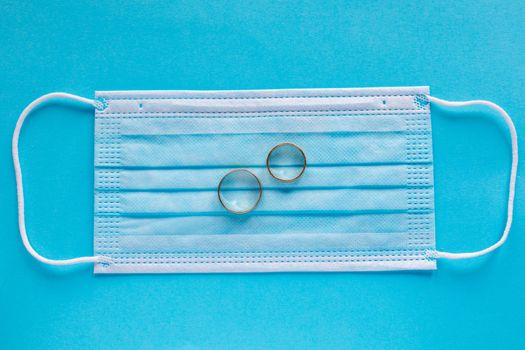 Wedding rings with surgical mask facemask - weddings and divorce concept in covid-19 pandemic time