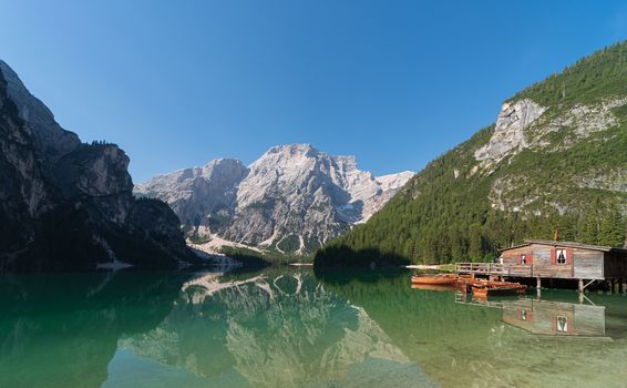 Panoramic view of Lake Braies and Seekofel mountain reflected in the water with a hut for boat rental