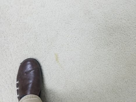 brown shoe on dirty stained white carpet or rug