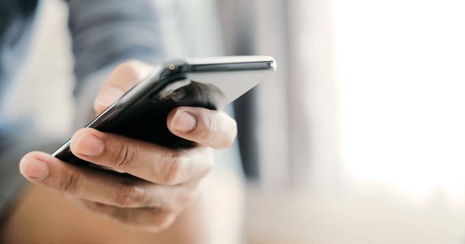 Close up man using smart phone at home.