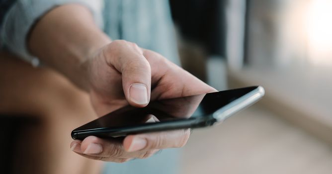 Close up man using smart phone at home.