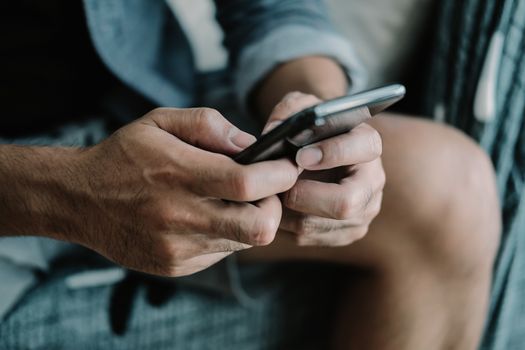 Close up man using smart phone at home.