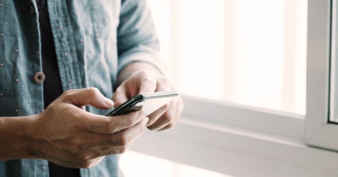 Close up man using smart phone at home.