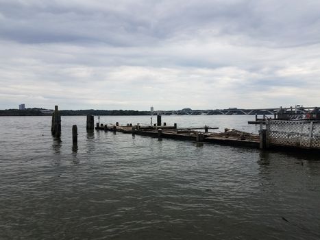 dilapidated old wood pier with drift wood and Wilson bridge in Alexandria, Virginia