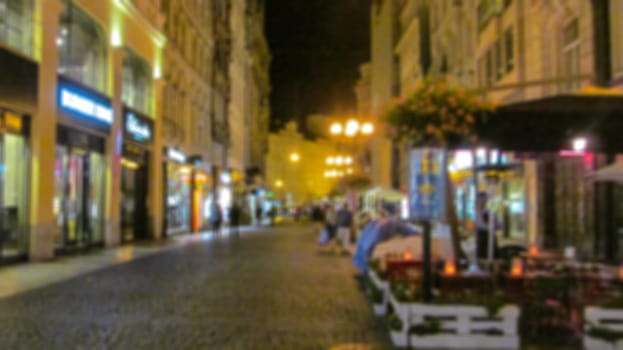 Blurred background. Evening city landscape, city street with lights and passers-by. Creative story for a background, poster, banner, or screensaver.
