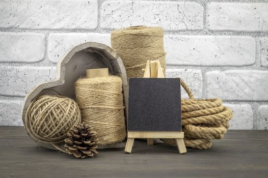 Assorted balls of hemp twine and string with skeins of rope and slate chalkboard in a close up rustic still life
