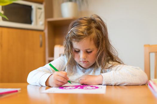 Focused happy cute girl with long curly golden hair artist painting picture on paper. School homework concept
