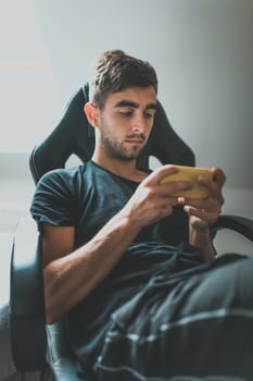 Young casual man holding and using smartphone for sms messages or social network, man watching cell phone. Technology and Social media network concept