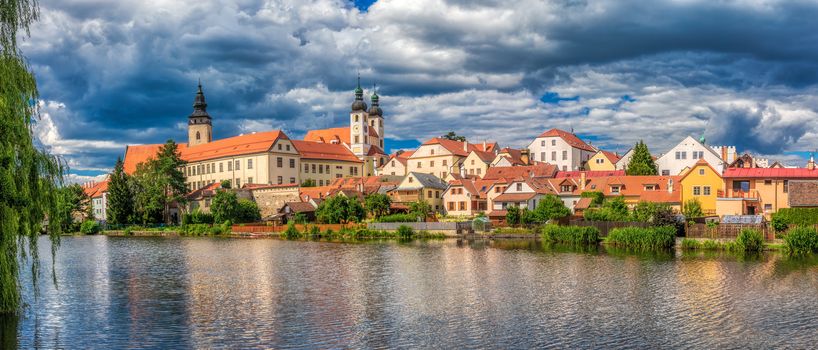 Telc city Panorama with dramatic sky. Water reflection of houses and Telc Castle, Czech Republic. UNESCO World Heritage Site.