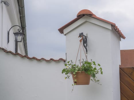 Decorative hanging flower pot in front of old white gate wall of farm house with lantern