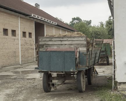 old truck with straw standing in front on barn, vintage look, faded colors, summer